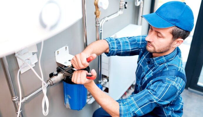young-man-in-workwear-using-pliers-while-installing-water-softener
