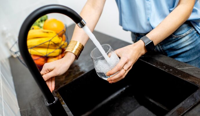 A female hand filling empty glass with tap water.