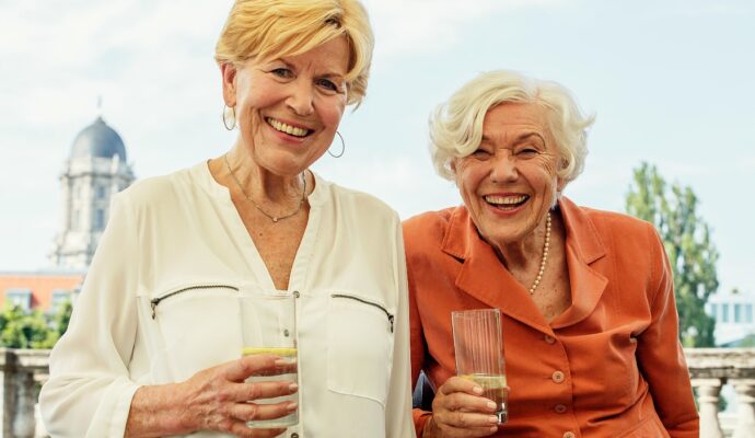 portrait of two smiling senior women with glasses of mineral water